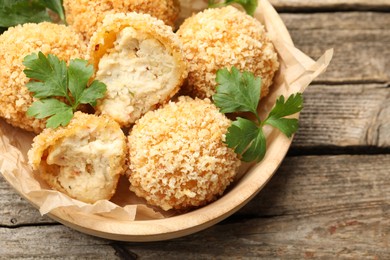 Photo of Delicious fried croquette balls with parsley on wooden table, above view