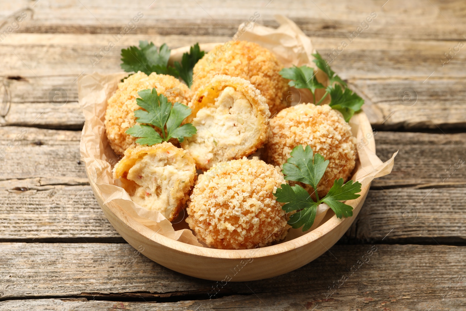 Photo of Delicious fried croquette balls with parsley on wooden table, closeup