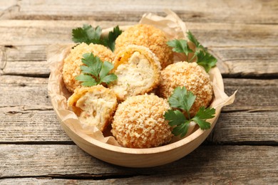 Photo of Delicious fried croquette balls with parsley on wooden table, closeup