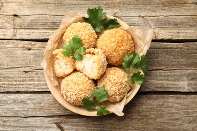 Photo of Delicious fried croquette balls with parsley on wooden table, top view