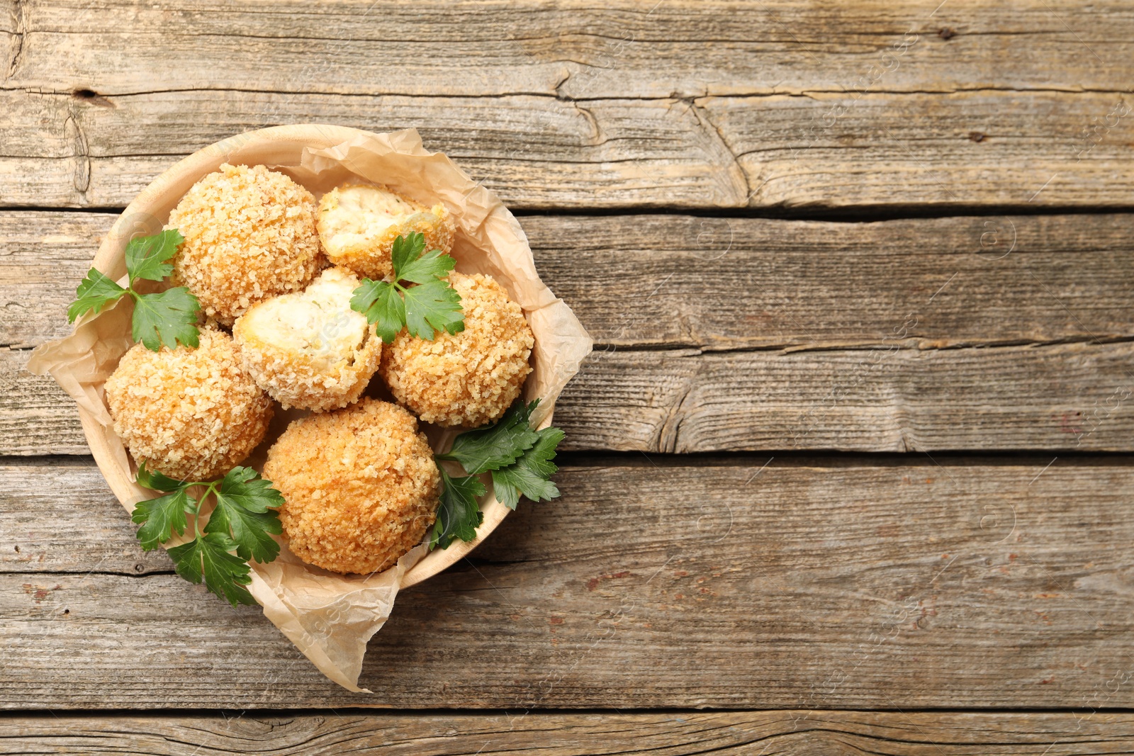 Photo of Delicious fried croquette balls with parsley on wooden table, top view. Space for text