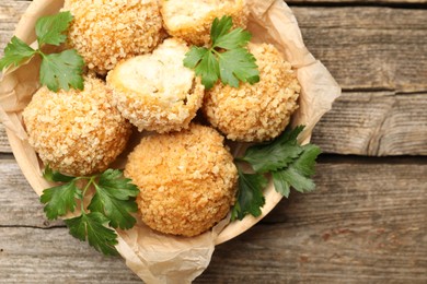 Photo of Delicious fried croquette balls with parsley on wooden table, top view
