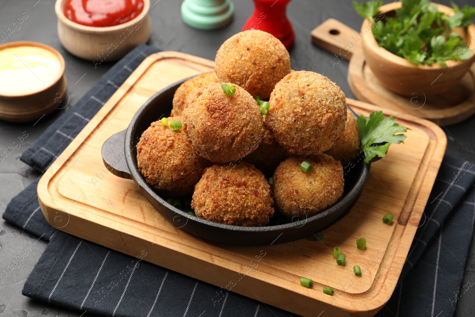 Delicious fried croquette balls with parsley and green onion on grey table, closeup Photo of Delicious fried croquette balls with parsley and green onion on grey table, closeup