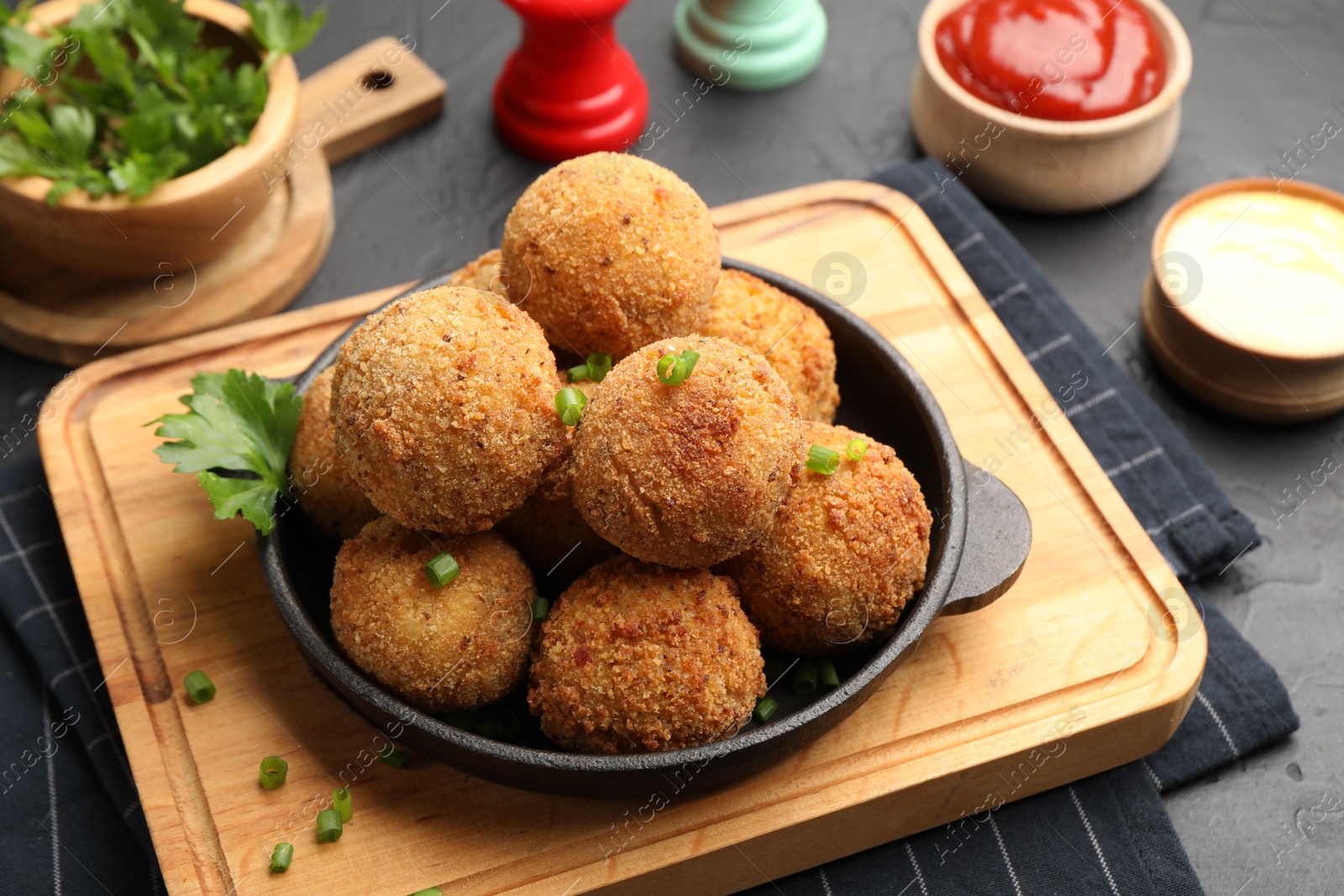 Delicious fried croquette balls with parsley and green onion on grey table, closeup Photo of Delicious fried croquette balls with parsley and green onion on grey table, closeup