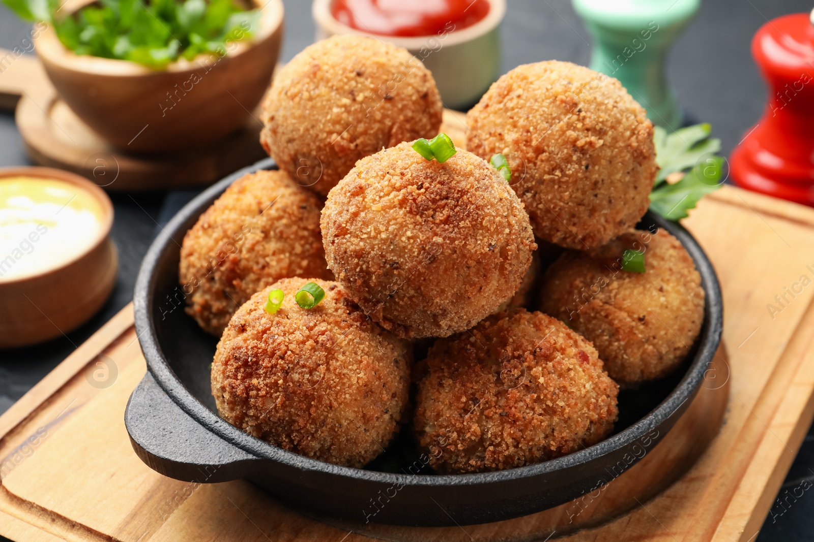 Photo of Delicious fried croquette balls with green onion on grey table, closeup
