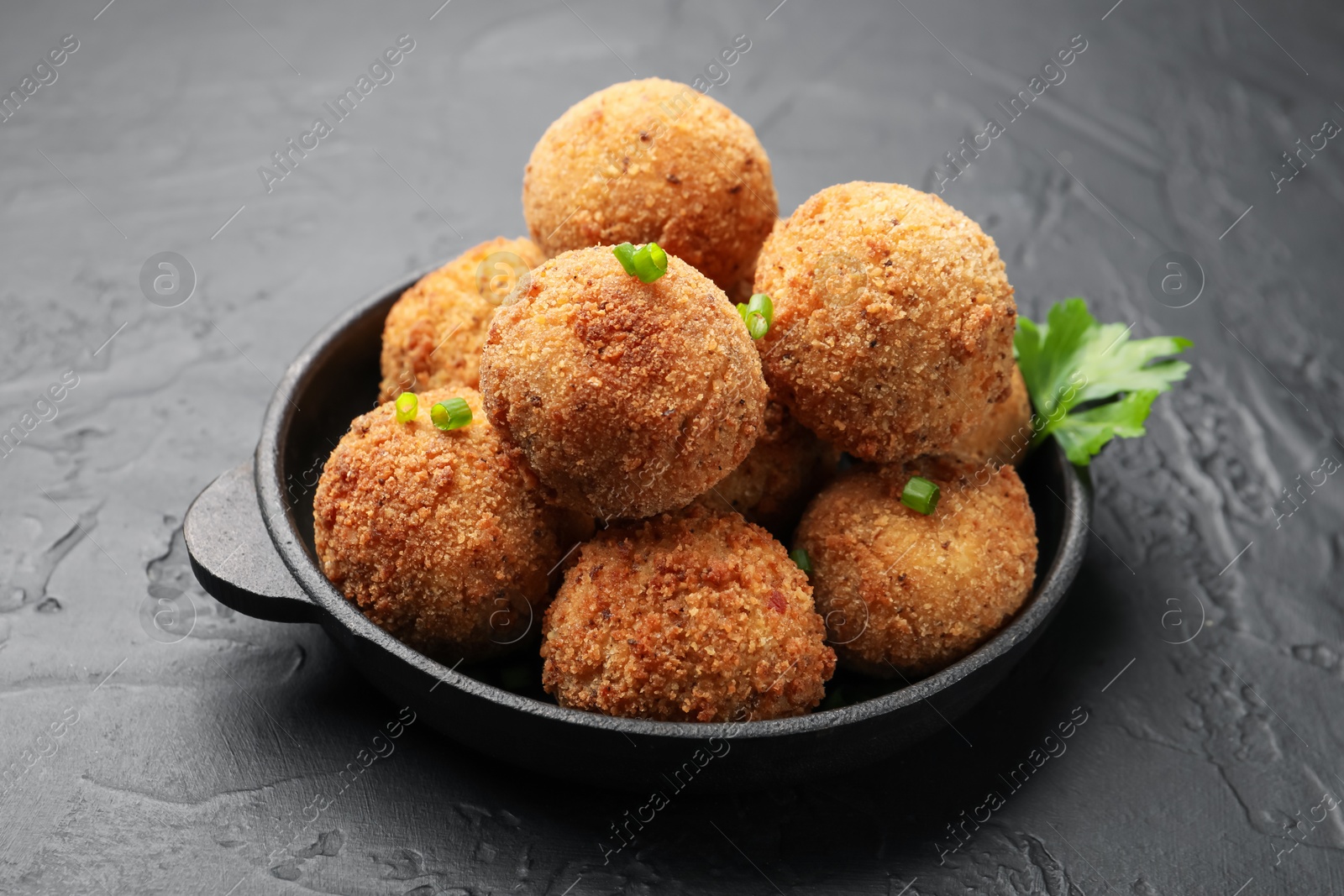 Delicious fried croquette balls with parsley and green onion on grey textured table, closeup Photo of Delicious fried croquette balls with parsley and green onion on grey textured table, closeup