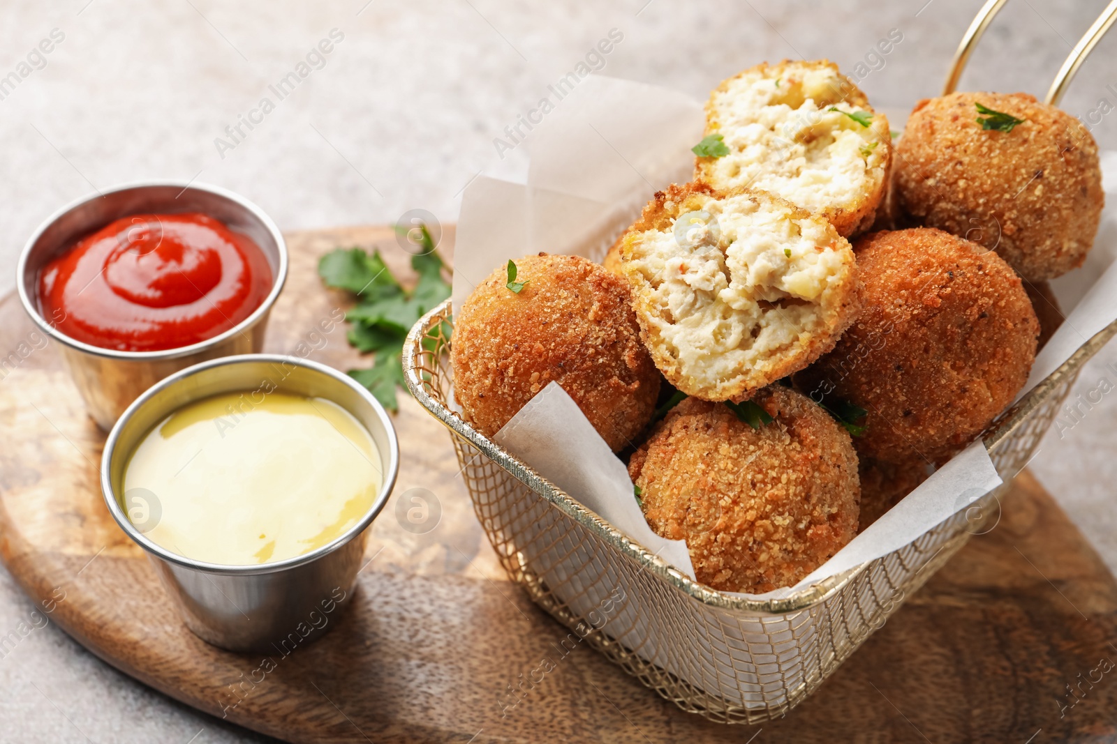 Delicious fried croquette balls with parsley and sauces on grey textured table, closeup Photo of Delicious fried croquette balls with parsley and sauces on grey textured table, closeup
