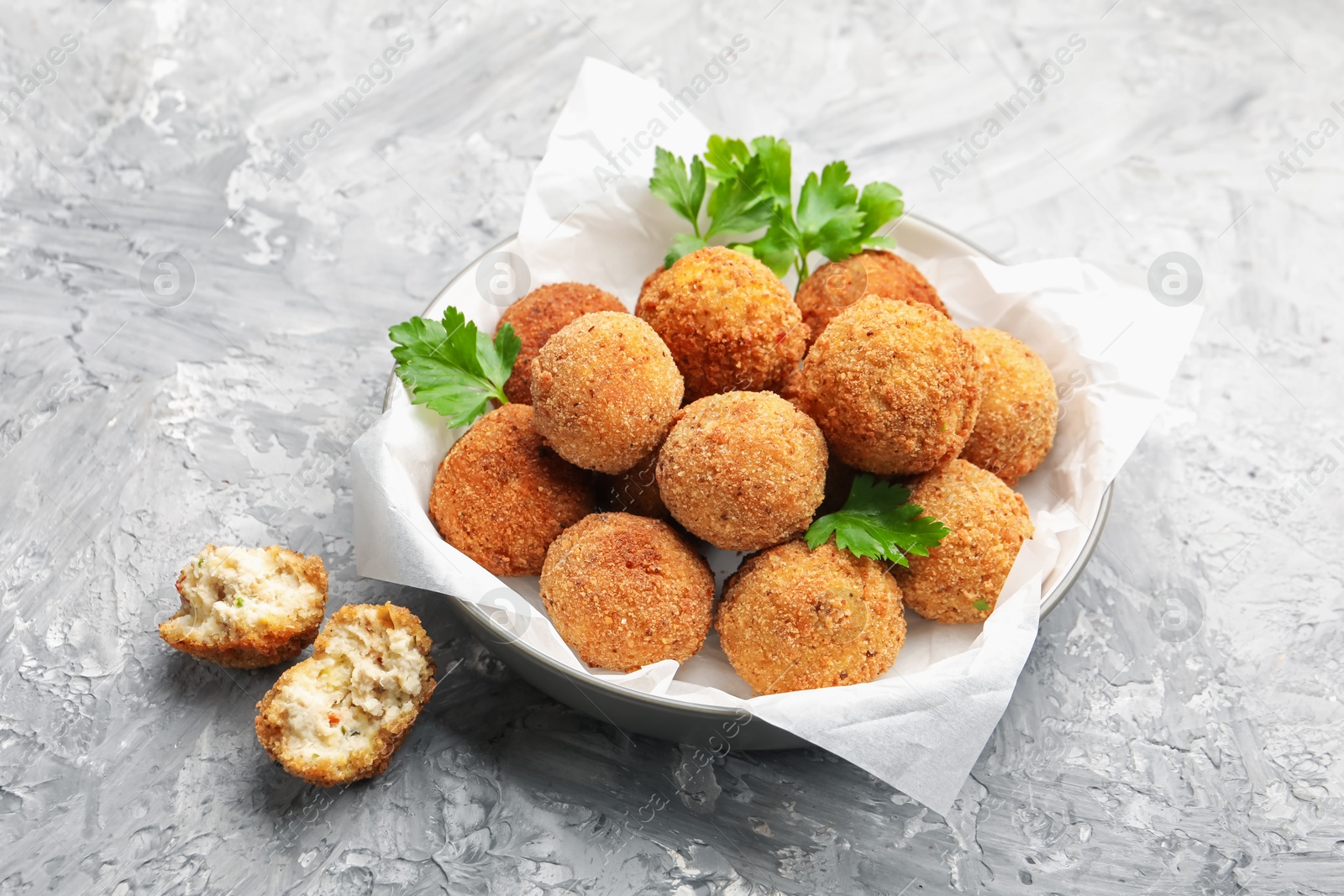 Delicious fried croquette balls with parsley in bowl on grey textured table, closeup Photo of Delicious fried croquette balls with parsley in bowl on grey textured table, closeup