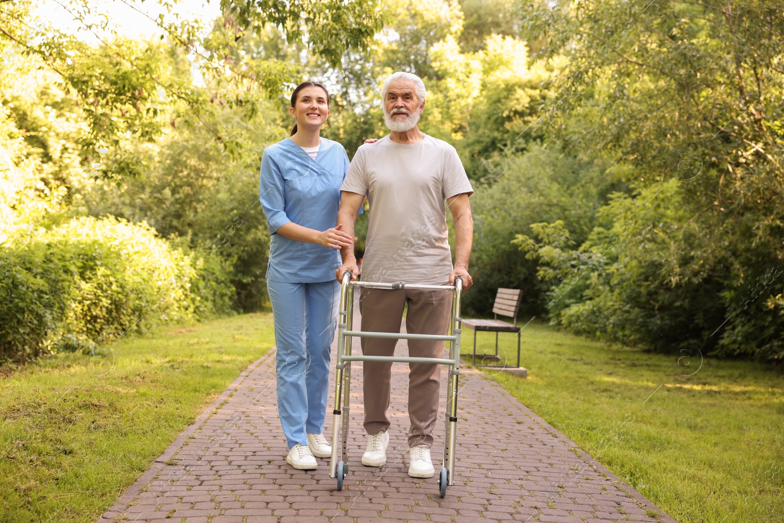 Smiling nurse supporting elderly man who using walking frame outdoors Photo of Smiling nurse supporting elderly man who using walking frame outdoors