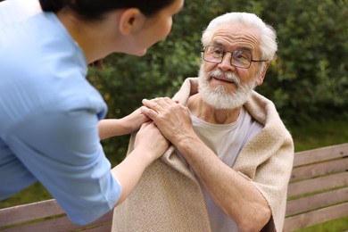 Photo of Nurse supporting smiling elderly man in glasses outdoors, closeup