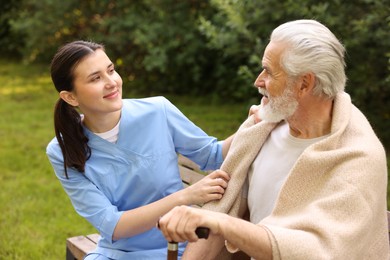 Photo of Nurse with elderly man on bench outdoors