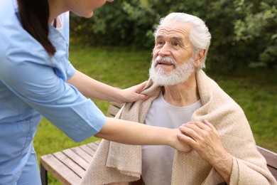 Photo of Nurse supporting smiling elderly man outdoors, closeup