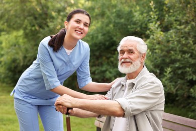 Photo of Portrait of smiling nurse and elderly man with walking cane outdoors
