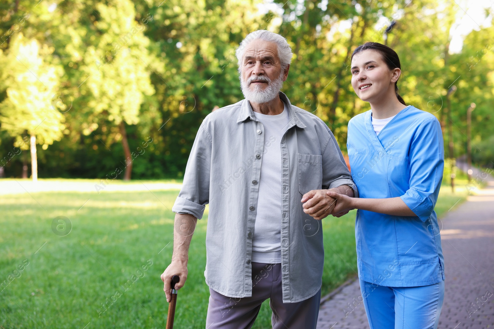 Smiling nurse supporting elderly man with walking cane outdoors Photo of Smiling nurse supporting elderly man with walking cane outdoors