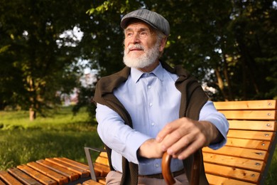 Photo of Handsome elderly man with walking cane sitting on bench outdoors