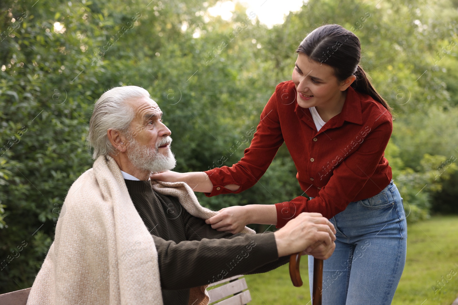 Smiling caregiver supporting elderly man with walking cane outdoors Photo of Smiling caregiver supporting elderly man with walking cane outdoors
