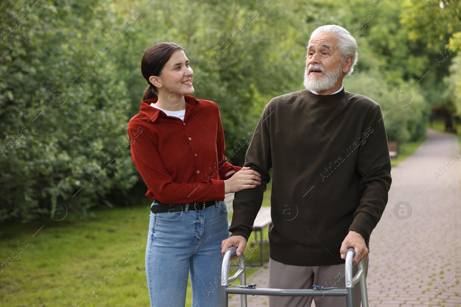 Smiling caregiver supporting elderly man who using walking frame outdoors Photo of Smiling caregiver supporting elderly man who using walking frame outdoors