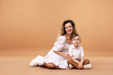 Photo of Family. Happy mother and her son posing on beige background. Space for text