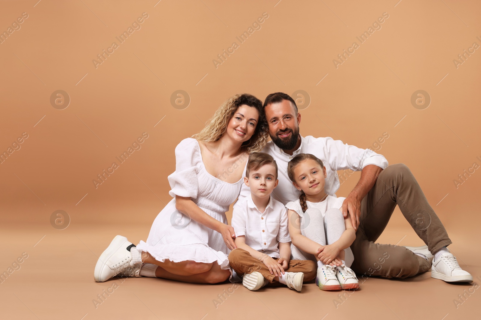 Happy family posing on beige background. Space for text Photo of Happy family posing on beige background. Space for text