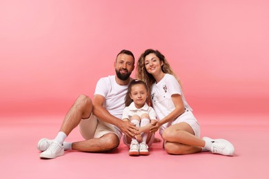 Photo of Family. Happy parents and their daughter posing on pink background