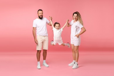 Photo of Family. Happy parents and their daughter on pink background