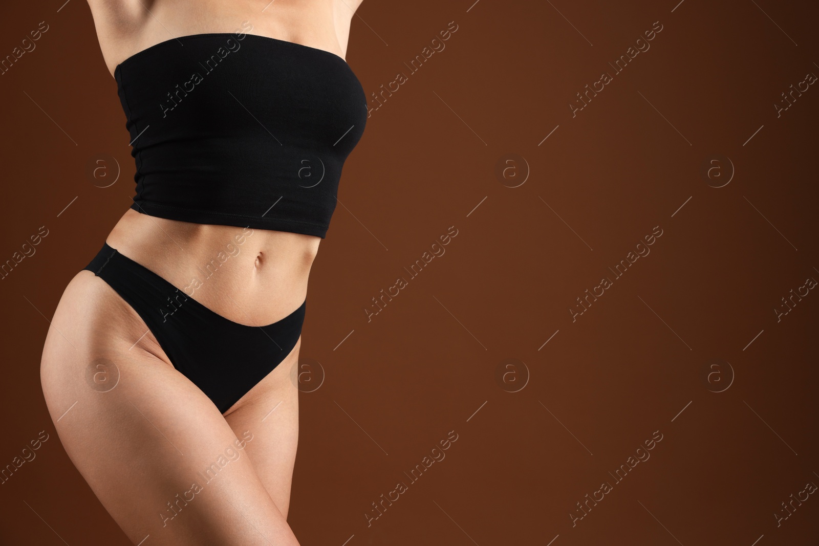 Fit woman with perfect body on brown background, closeup. Space for text Photo of Fit woman with perfect body on brown background, closeup. Space for text