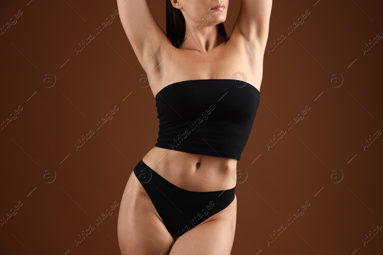Fit woman with perfect body on brown background, closeup Photo of Fit woman with perfect body on brown background, closeup