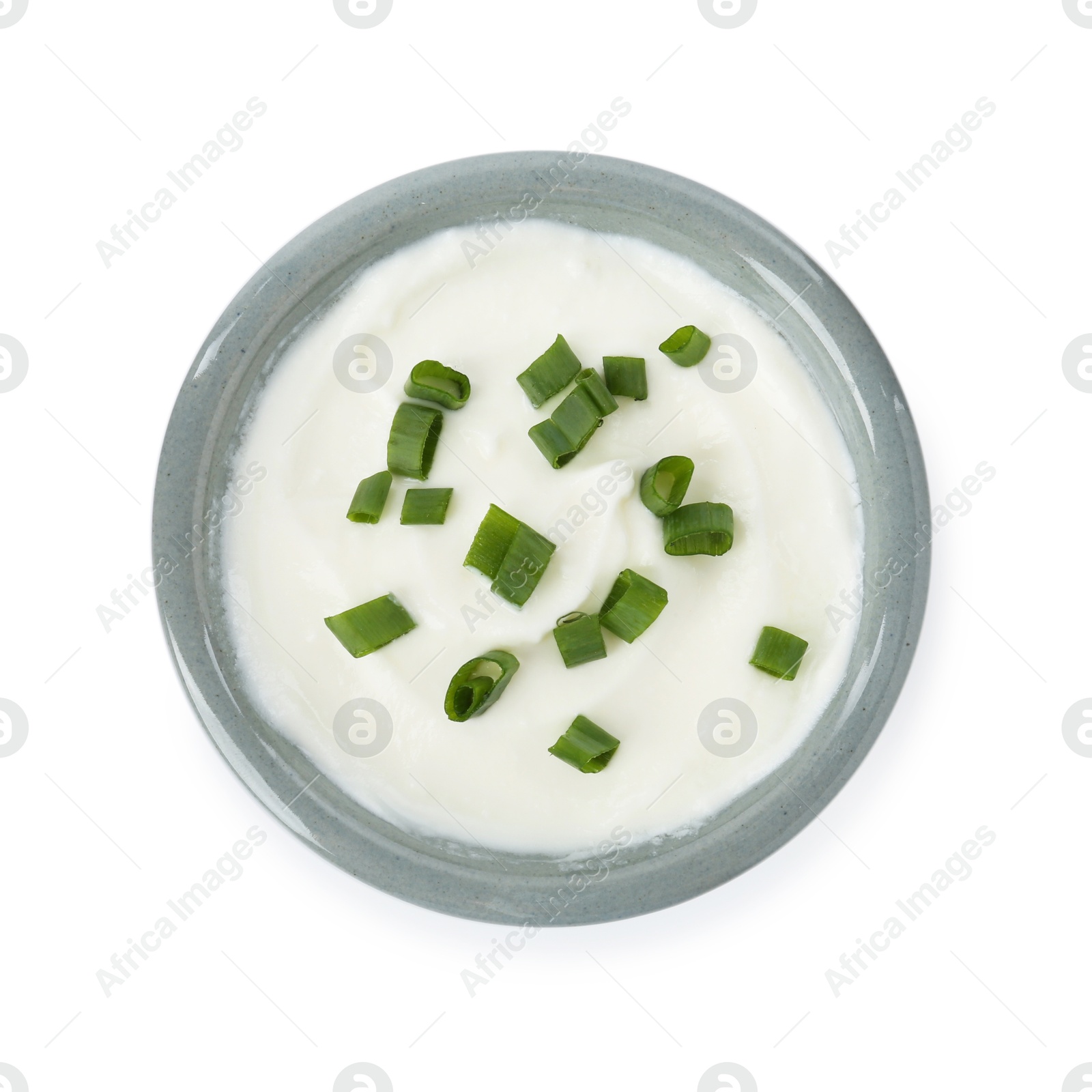 Photo of Tasty yoghurt with green onions in bowl isolated on white, top view