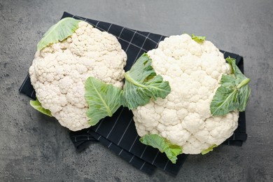 Photo of Fresh cauliflower heads with green leaves on grey table, flat lay