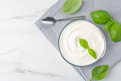 Photo of Tasty yoghurt with basil in bowl on white marble table, flat lay. Space for text