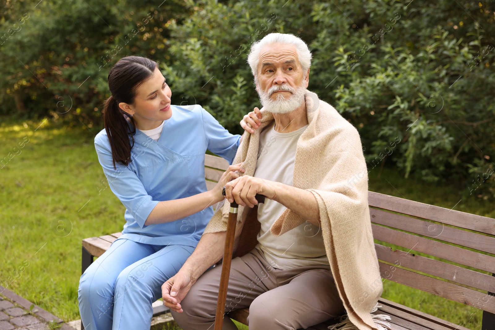 Nurse with elderly man on bench outdoors Photo of Nurse with elderly man on bench outdoors