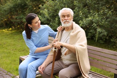 Photo of Nurse with elderly man on bench outdoors