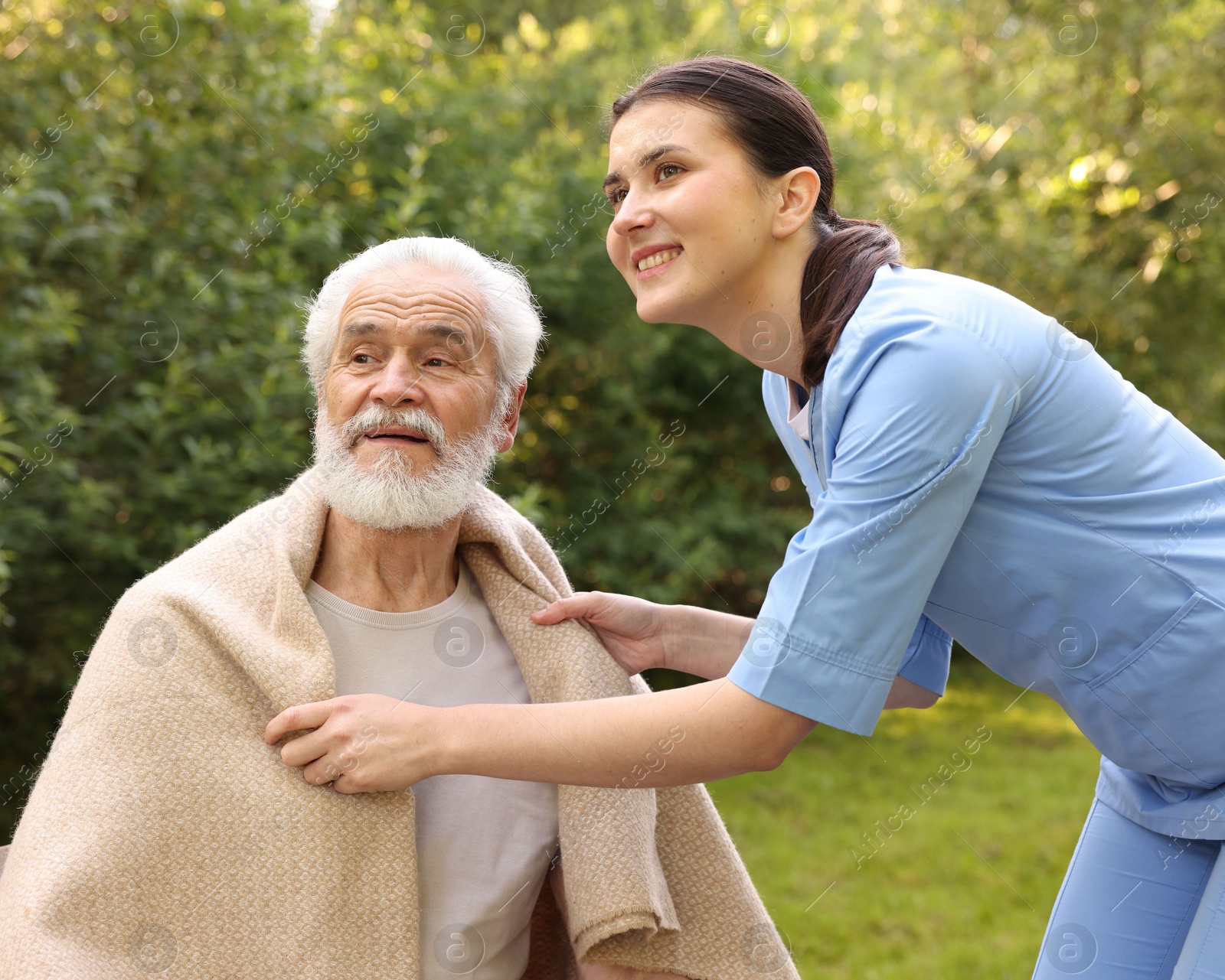 Smiling nurse with elderly man wrapped in blanket outdoors Photo of Smiling nurse with elderly man wrapped in blanket outdoors