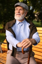Photo of Handsome elderly man with walking cane sitting on bench outdoors