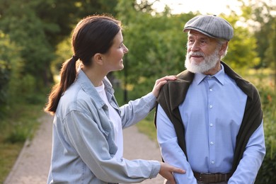 Photo of Caregiver supporting elderly man in summer park