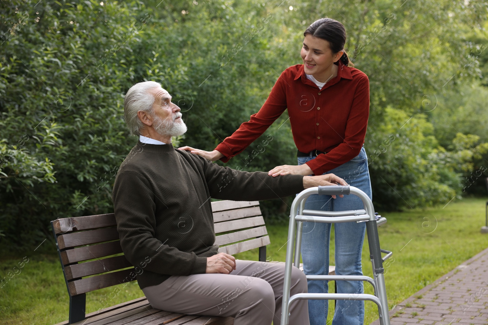 Smiling caregiver supporting elderly man with walking frame outdoors Photo of Smiling caregiver supporting elderly man with walking frame outdoors