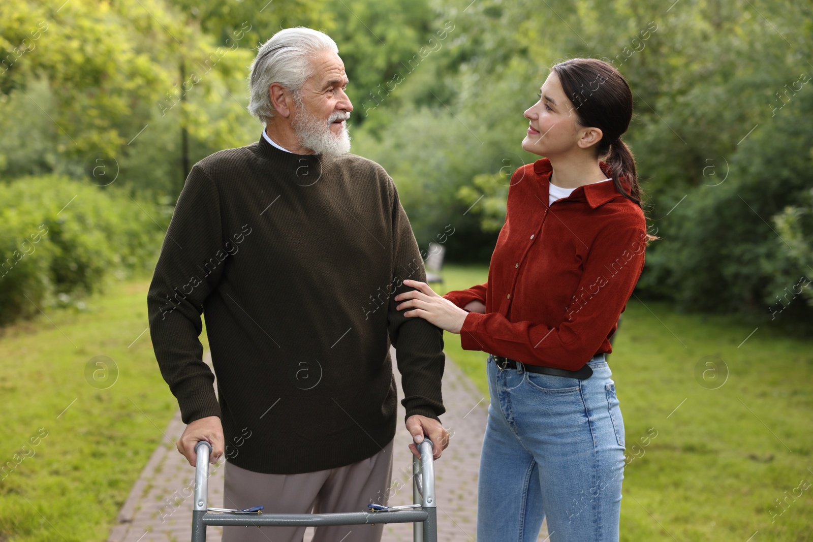 Caregiver supporting elderly man who using walking frame outdoors Photo of Caregiver supporting elderly man who using walking frame outdoors