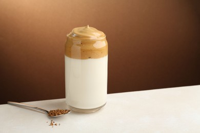Photo of Delicious dalgona coffee in glass and granules on white table, space for text