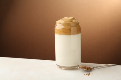 Photo of Delicious dalgona coffee in glass and granules on white table, space for text
