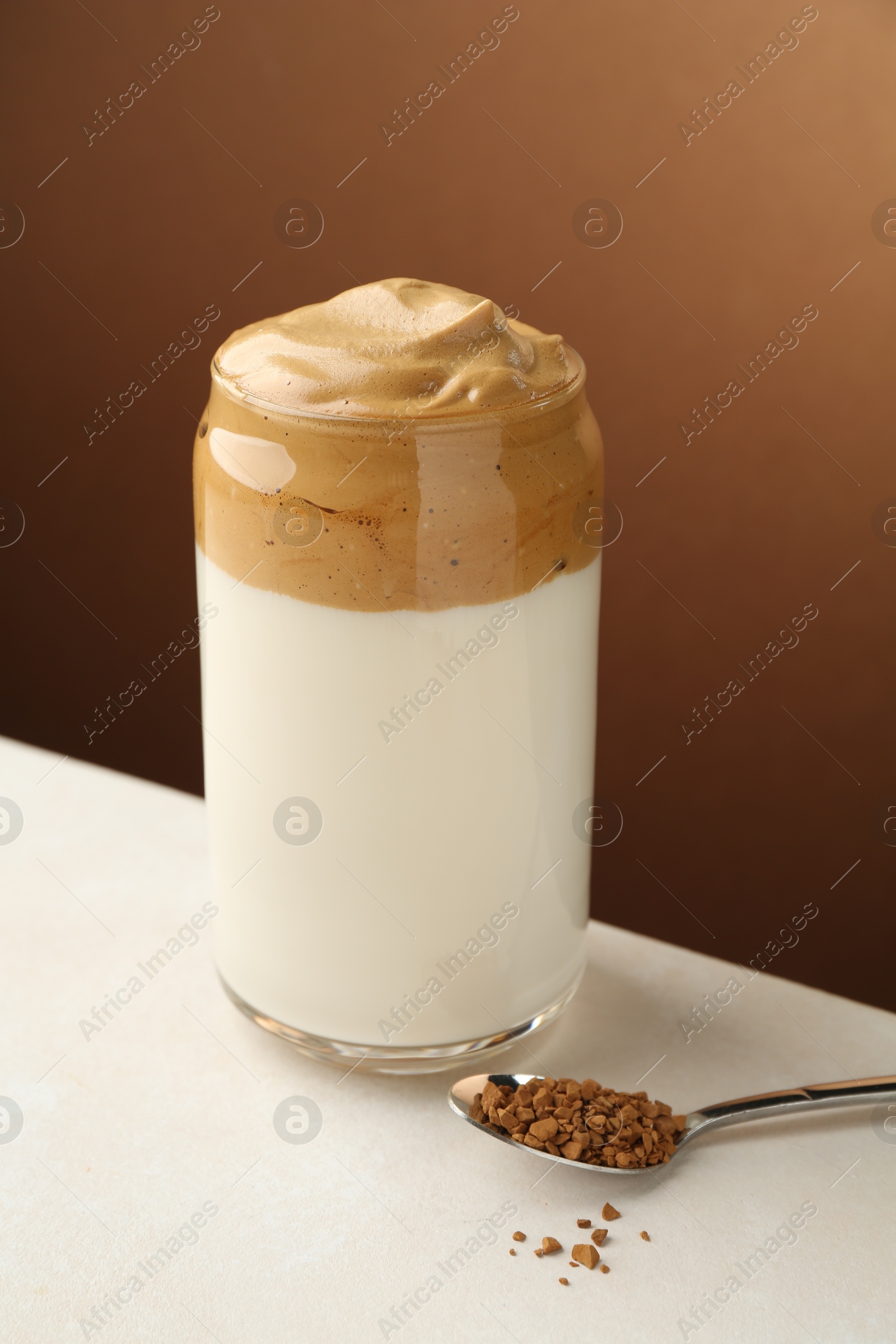 Photo of Delicious dalgona coffee in glass and granules on white table