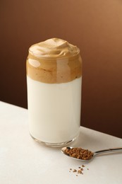 Photo of Delicious dalgona coffee in glass and granules on white table