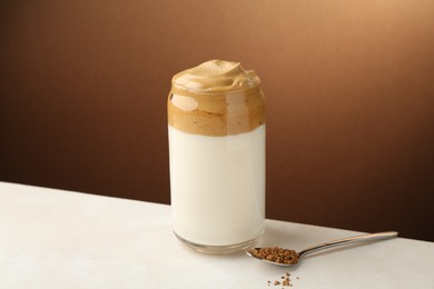 Photo of Delicious dalgona coffee in glass and granules on white table