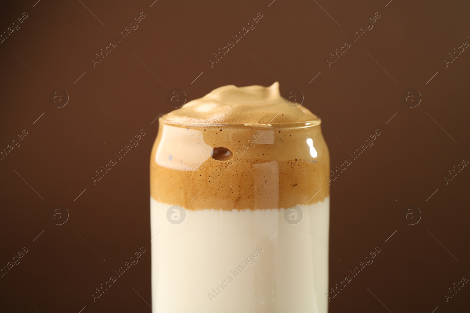 Photo of Delicious dalgona coffee in glass on brown background, closeup