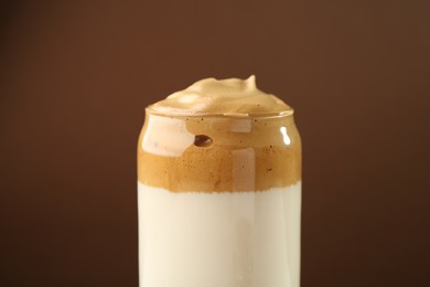 Photo of Delicious dalgona coffee in glass on brown background, closeup