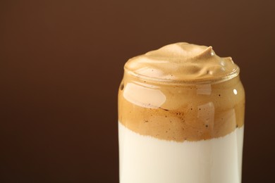 Photo of Delicious dalgona coffee in glass on brown background, closeup. Space for text