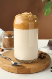 Photo of Delicious dalgona coffee in glass, beans and granules on white table, closeup