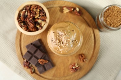 Photo of Delicious dalgona coffee in glass, pieces of chocolate, walnuts and granules on table, flat lay
