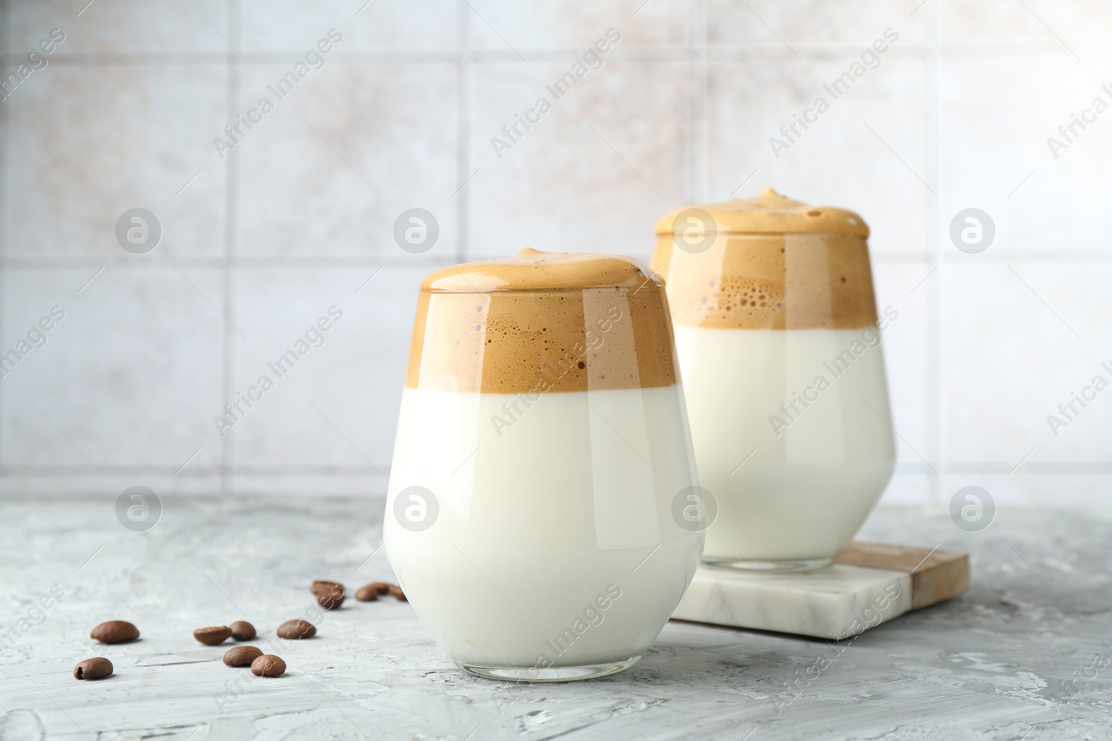 Photo of Delicious dalgona coffee in glasses and beans on grey table, closeup