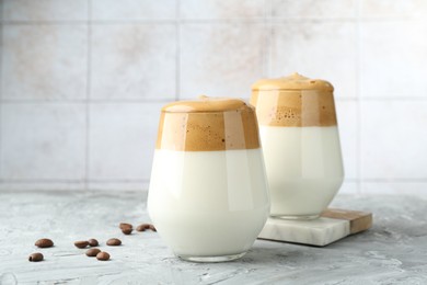 Photo of Delicious dalgona coffee in glasses and beans on grey table, closeup