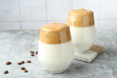 Photo of Delicious dalgona coffee in glasses and beans on grey table, closeup